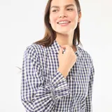 Pijama de dos piezas confeccionado en popelina con estampado de cuadros vichy. Incluye una camisa de manga larga con cuello camisero, cierre frontal de botones y puños con volados, y un pantalón de corte recto con terminación de volado en el ruedo.