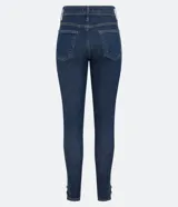 Pantalón skinny jeans azul oscuro con trabillas en la cintura, bolsillos y detalle de pespuntes contrastantes. La pieza también tiene dos botones dorados a cada lado de la barra.