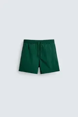 Bañador de hombre color verde oscuro, de largo medio, con cintura elástica ajustable con cordón, bolsillos laterales y bolsillo trasero de plastrón. Incluye forro interior.