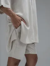 Camisa de corte oversize en color beige, confeccionada en tejido de lino y algodón. Presenta cuello clásico, cierre frontal con botones y mangas cortas amplias.