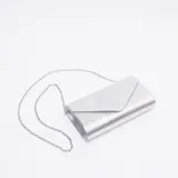 Sobre de fiesta tipo clutch con acabado texturizado metalizado, solapa triangular y cadena metálica fina extraíble para llevar al hombro.