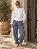 Pantalón azul marino de corte amplio y holgado, con pliegues en la cintura y ajuste con lazo en los tobillos.