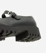 Zapato estilo Mary Jane de la marca Satinato, color negro, confeccionado en poliuretano con suela tractorada de goma, punta redonda y tira en el empeine con hebilla metálica ajustable.