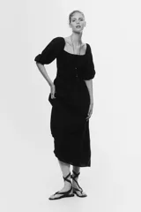 Vestido midi negro confeccionado en mezcla de viscosa, con escote cuadrado y mangas francesas abullonadas con puños elásticos. Presenta un cuerpo fruncido tipo nido de abeja y una falda de corte acampanado con leve vuelo.