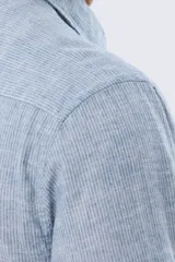 Camisa de manga larga confeccionada en mezcla de lino y algodón, con sutiles rayas celestes, cuello camisero clásico y cierre frontal de botones.