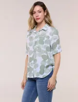 Camisa de lino sintético con estampado floral en tonos azules y beige sobre fondo blanco, de corte holgado, mangas tres cuartos y cuello camisero.