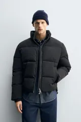 Cazadora negra boxy fit confeccionada en tejido técnico repelente al agua, con cuello subido, manga larga con puño interior elástico, bolsillos de vivo en cadera, bolsillo interior, bajo ajustable con elástico oculto y cierre frontal con cremallera.