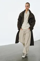Trench oversize de Zara Woman Collection, confeccionado en mezcla de algodón con estampado de cuadros pequeños. Presenta cuello alto, cierre frontal con botones, mangas largas con trabillas ajustables y bolsillos laterales.