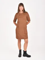 Vestido corto de gamuza color marrón, con cuello redondo, mangas cortas y dos bolsillos frontales tipo parche.