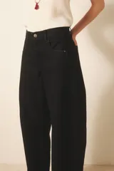 Jean de tiro medio-alto, color negro, de calce holgado con piernas anchas que se estrechan hacia el tobillo. Presenta pinzas en las rodillas que acentúan su forma "balloon" y un recorte lateral. Confeccionado en denim rígido con lavado suavizado, cierre y botón.