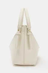 Bolso tipo mini shopper de diseño estructurado en color beige, con forma de V en la parte superior y asa de mano fija. Presenta costuras visibles y detalles metálicos en los laterales.