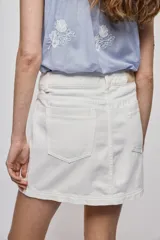 Falda de denim blanca de corte recto con bolsillos delanteros aplicados, costuras pespunteadas a contratono y cierre frontal con botón y cremallera.