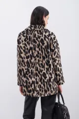 Tapado cruzado de corte oversize confeccionado en paño con estampado de leopardo. Presenta solapas clásicas, cierre frontal con botones y bolsillos aplicados.