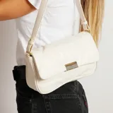 Cartera al hombro color blanco con diseño acolchado y cierre dorado.