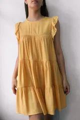 Vestido corto amarillo con corte evasé, cuello redondo y mangas cortas con volantes.