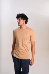 Remera de manga corta con cuello redondo, confeccionada en algodón de color beige. Presenta un pequeño logo bordado de un pingüino en el pecho.