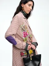 Blazer de corte recto con estampado de cuadros en tonos rosados, presenta bordados florales coloridos en el frente y un parche estilo escudo en el bolsillo superior. Cuenta con cierre frontal de botones y detalles en contraste en las mangas.
