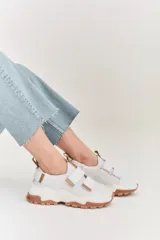 Championes de estilo urbano en color blanco con detalles en tono arena. Presentan un diseño con doble tira de velcro en el empeine, suela de plataforma dentada en color caramelo y tirador en el talón.