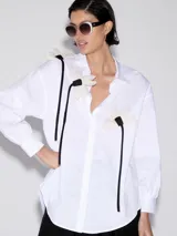 Camisa blanca de mangas largas con apliques de flores blancas y lazos negros.