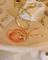 Collar con dije de bronce macizo con forma orgánica irregular, similar a un coral, suspendido de un cordón negro de seda natural anudado.