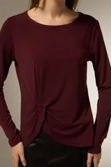 Remera de manga larga color bordó, confeccionada en viscosa, con cuello redondo y detalle de nudo lateral que genera un drapeado suave.