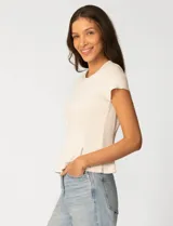 Remera blanca de manga corta con cuello redondo, confeccionada en una mezcla de modal, poliéster y elastano. Presenta un diseño con alforzas verticales en el frente que aportan estructura y una silueta relajada.