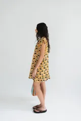 Vestido corto sin mangas en color rosado con estampado floral en blanco y negro. Presenta una cartera de botones asimétrica en el frente y detalle de volado fruncido en el ruedo. Confeccionado en algodón liviano.