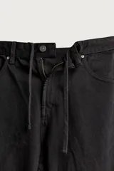 Pantalón barrel fit de mezclilla color verde militar, con efecto lavado, cinco bolsillos, cierre frontal con cremallera y botón, y detalle de pinzas en las rodillas.