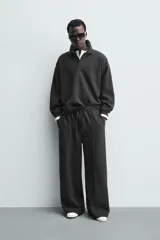 Pantalón de corte wide fit en tejido con acabado cepillado, color gris oscuro. Presenta cintura elástica con cordón ajustable, bolsillos delanteros y bolsillos traseros de plastrón.
