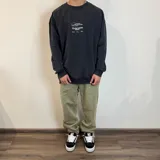 Buzo negro con estampado en la espalda con motivos playeros y texto en blanco y naranja.