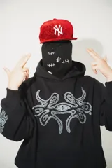 Hoodie negro oversize de algodón con capucha y pasamontañas desmontable con cierre. Presenta estampa en plastisol en el pecho y en ambas mangas.