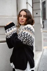 Sweater de lana con diseño de jacquard en la parte superior, cuello redondo, mangas largas y puños acanalados. Presenta un corte holgado con tajos laterales y un diseño ligeramente más corto en la parte delantera.