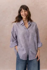 Camisa lila oversize de algodón con bordado floral calado tipo broderie, cuello camisero, manga larga y abotonadura frontal.
