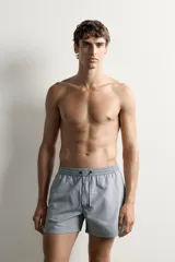 Short de baño confeccionado en tejido técnico con patrón de rayas verticales en tonos azul marino y blanco, con cintura elástica ajustable mediante cordón y bolsillos laterales.