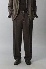 Pantalón relaxed fit de traje color marrón oscuro, confeccionado en tejido con mezcla de algodón. Cuenta con bolsillos frontales, bolsillos traseros de doble vivo con botón y efecto lavado. Cierre frontal con cremallera y botón.
