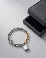 Pulsera de eslabones gruesos en acero plateado, combinada con un eslabón en baño de oro y un dije central en forma de candado plateado.