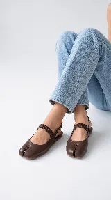 Chatitas estilo Tabi en cuero color chocolate, con diseño de punta dividida, tira elástica fruncida en el empeine y tira trasera con hebilla ajustable.
