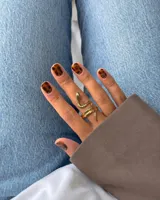 Anillo de acero dorado con diseño en forma de serpiente enrollada alrededor del dedo.