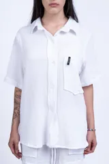 Camisa negra de manga corta con cuello clásico, bolsillo en el pecho y corte holgado.