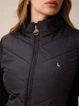 Campera acolchada con frente y espalda en tejido técnico, combinada con mangas y laterales de tejido liso. Presenta cuello alto, cierre frontal completo y bolsillos laterales. Incluye un pequeño detalle bordado en el pecho.