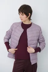 Campera acolchada tipo puffer en color beige, con diseño sin cuello y cierre frontal con botones a presión.