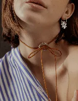 Choker marrón de gamuza con un dije circular de strass en el centro, atado con un lazo.
