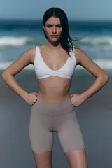 Top deportivo blanco para yoga, con escote en V, breteles anchos y detalle girado en el frente. Incluye copas forradas con relleno extraíble.