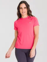 Remera deportiva de manga corta en color fucsia, con cuello redondo y diseño ergonómico. Presenta un pequeño logo reflectante en el pecho y una apertura en la espalda para mayor ventilación.