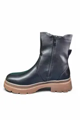 Bota de caña media color negro, estilo chelsea, con paneles elásticos laterales y suela track dentada.