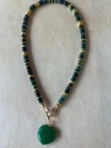 Collar con dije de corazón facetado en color verde esmeralda, con cadena de cuentas de cristal facetadas en tonos amarillos y dorados.