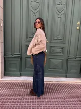 Pantalón tipo jean cargo de corte ancho y tiro alto, confeccionado en denim azul oscuro. Presenta bolsillos laterales tipo cargo con solapa y costuras reforzadas a lo largo de las piernas.