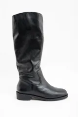 Bota de caña alta confeccionada en cuero legítimo negro, con diseño de textura granulada en la parte superior y acabado liso en la puntera. Cuenta con un taco bajo y suela plana.