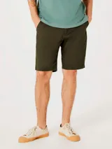 Bermuda recta estilo chino para hombre, confeccionada en lino color beige, con bolsillos laterales y traseros, y cierre frontal con botón y cremallera.