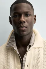 Cárdigan de ajuste relajado, tejido en hilado con lana, color crema. Presenta cuello solapa, manga larga y textura de punto trenzado en todo el cuerpo. Cierre frontal con botones.